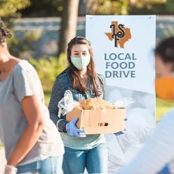 A volunteer carrying a box of donated food